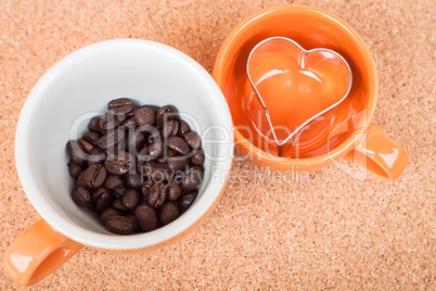 Cup of coffee bean and cookies cutter on cork background
