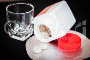 Open pill bottle with brown medicine spilling out