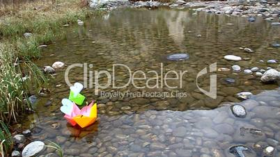 Colored paper boats floating on a small lake