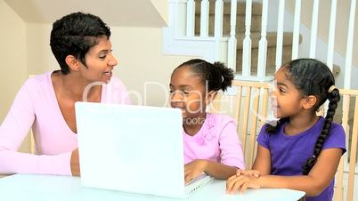Ethnic Mother Watching Daughters Using Laptop