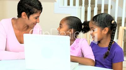 Ethnic Mother Watching Daughters Using Laptop