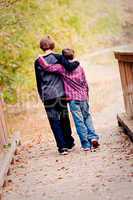 Two brothers hugging and walking on bridge