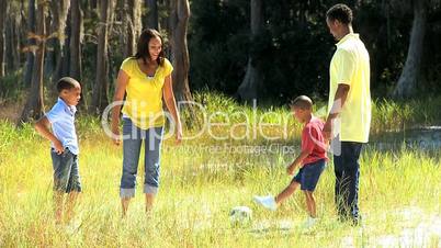 African American Family Playing Football in Park