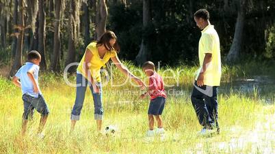 Happy Ethnic Family Kicking a Ball in the Park