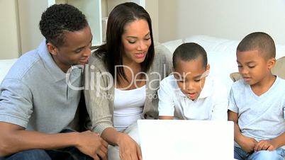 Ethnic Parents Watching Young Sons Using Laptop