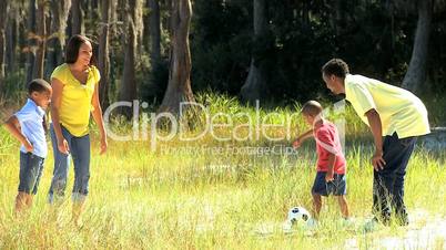 Young Family Kicking a Ball in the Park