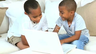 Little Ethnic Boys with Laptop on Sofa