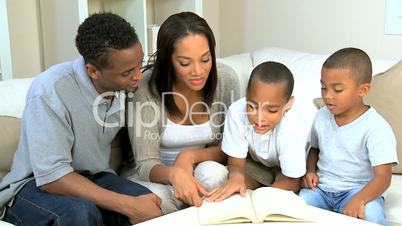 Proud Young Parents Listening to their Son Reading