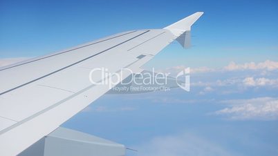 Wing of airplane and blue sky with clouds