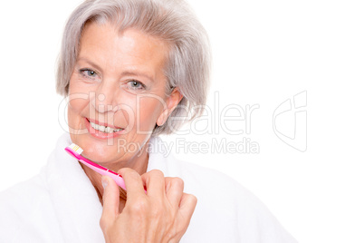 Seniorin im Bademantel und mit Zahnbürste