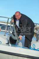 Fat man in tuxedo lifting an anchor