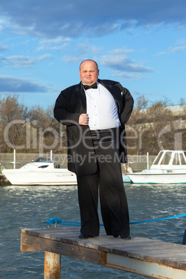 Fat man in tuxedo on pier