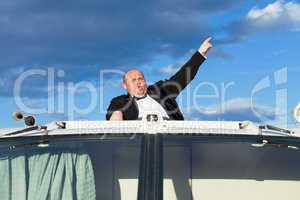 Overweight man in a tuxedo at the helm of a pleasure boat