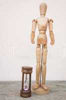 wood mannequin and hourglass to represent time over