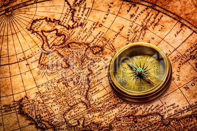 Vintage compass lies on an ancient world map.