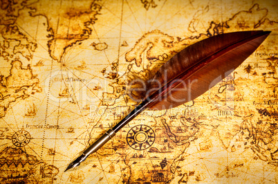 Vintage goose quill pen lying on an old map.