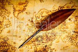 Vintage goose quill pen lying on an old map.