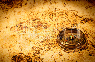 Vintage compass lies on an ancient world map.