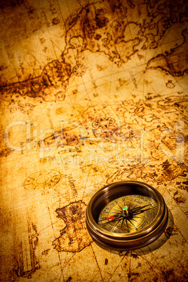 Vintage compass lies on an ancient world map.