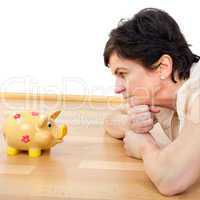 Woman looks thoughtfully at the piggy bank