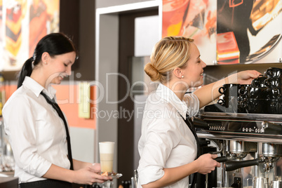 Two waitresses serving coffee with machine