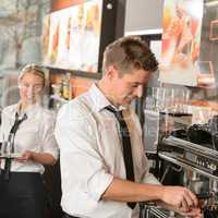 Young waiter and waitress working in bar