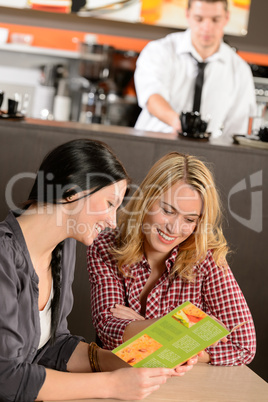 Young female customers reading menu in pub