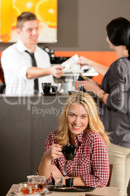 Happy female customer drinking espresso in cafe