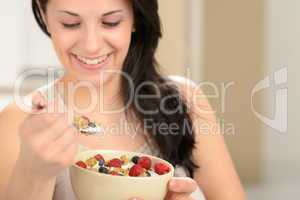 Joyful woman eating healthy cereal for breakfast