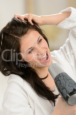 Joyful girl singing with blow dryer