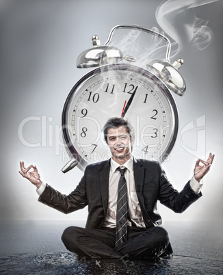 Businessman meditating in front of alarm clock