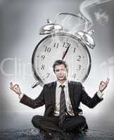 Businessman meditating in front of alarm clock