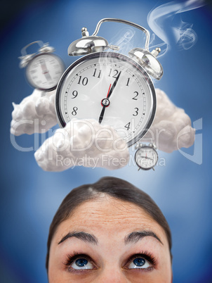 Woman looking up at ringing alarm clocks in clouds