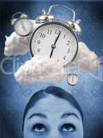 Woman looking up at alarm clock in clouds