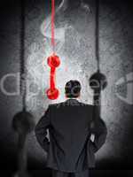 Businessman looking at hanging telephone receiver