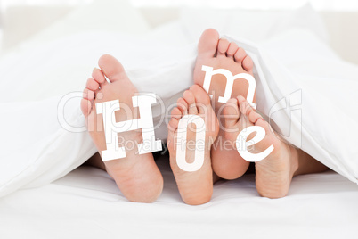 Pair of feet under the duvet with home text