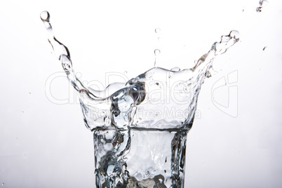 Close up on ice cube falling into a glass