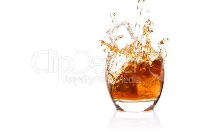 Ice cube falling into glass of whisky