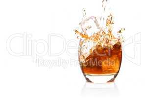 Ice cube falling into glass of whisky