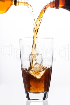 Two bottles pouring into a glass with ice cube