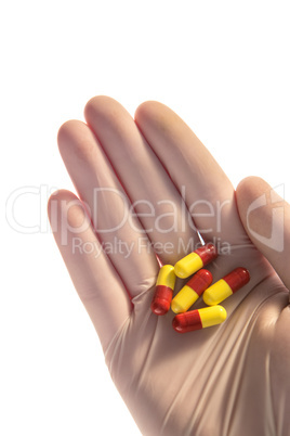 Gloved hand holding tablets in palm