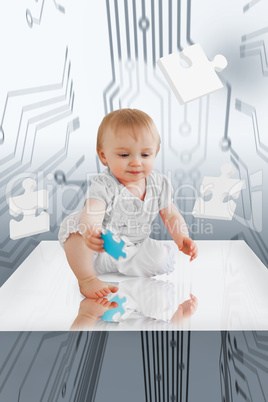 Baby holding jigsaw piece sitting on reflective surface
