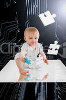 Baby holding jigsaw piece sitting on white reflective surface