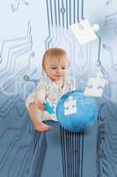 Baby holding jigsaw piece sitingt next to a globe