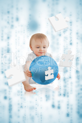 Cute baby holding a blue planet with jigsaw pieces floating arou