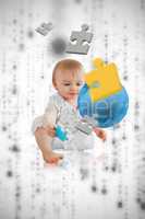 Jigsaw pieces floating around a cute baby playing with a blue pl