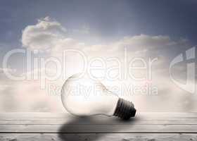 Light bulb resting on floorboards in the sky