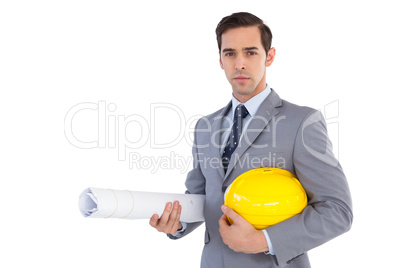 Serious architect holding plans and hard hat Serious architect holding plans and hard hat