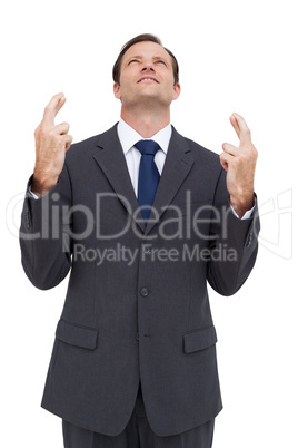 Businessman with fingers crossed is looking up