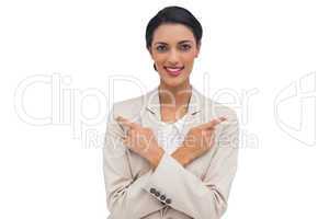Smiling businesswoman with her arms crossed and fingers pointing